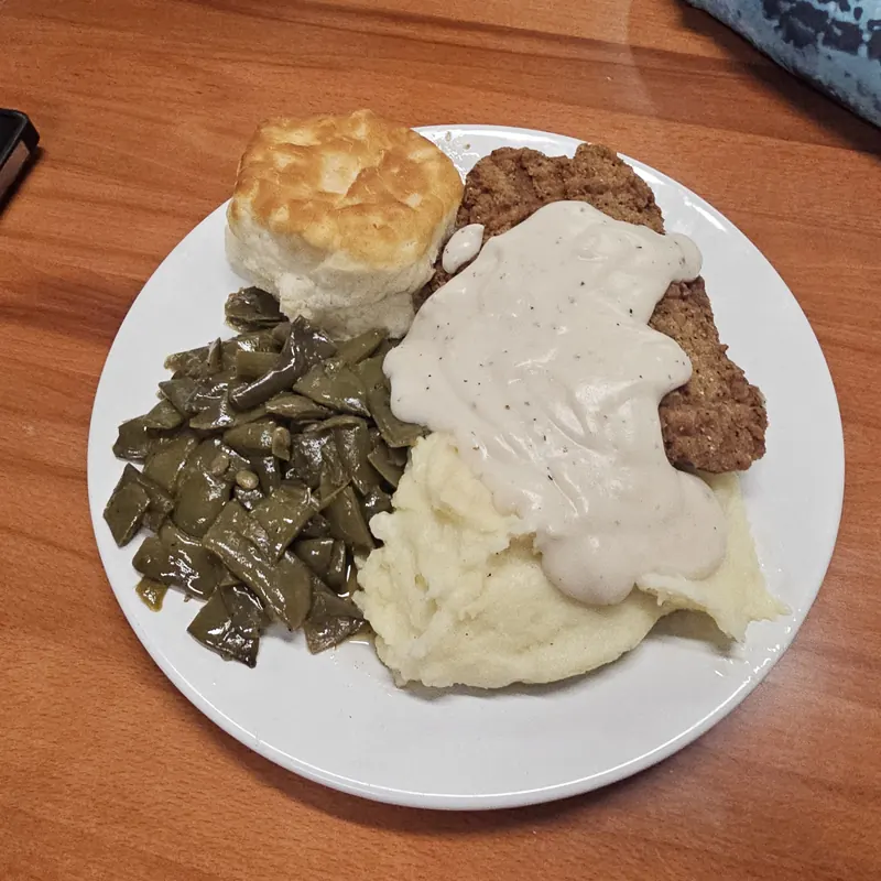 Country fried steak with white gravy, green beans, mashed potatoes and a biscuit